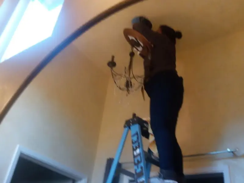 Electrician installing a chandelier in a Southgate residence